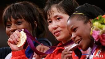 North Korea's An Kum Ae celebrates her gold medal victory next to silver medallist, Cuba's Yanet Bermoy Acosta (R) and bronze medallist France's Priscilla Gneto (L) during the awards ceremony for the women's 52kg judo competition at the London 2012 Olympic Games July 29, 2012.