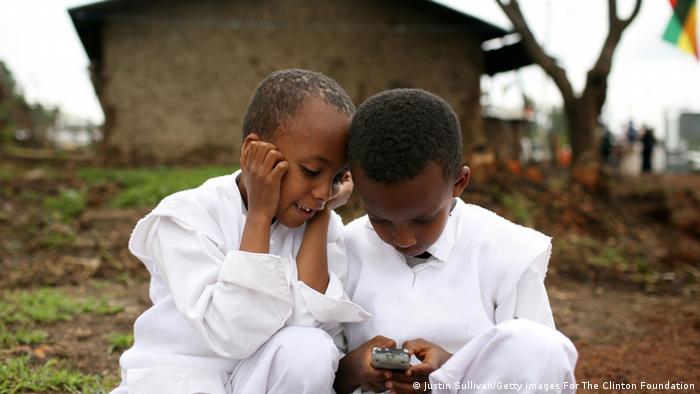 Two children in Ethiopia play with a mobile phone.