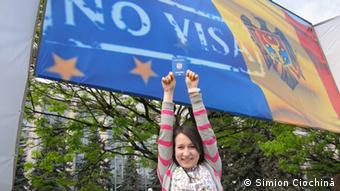 Девушка с молдавским паспортом на фоне плаката, посвященного безвизовому режиму с ЕС