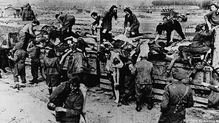 Бывшие надзиратели и охранники концлагеря убирают тела умерших узников под охраной британских солдат