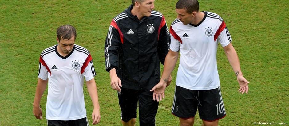 Os jogadores Philipp Lahm, Bastian Schweinsteiger e Lukas Podolski conversam na saída de um treino da seleção alemã