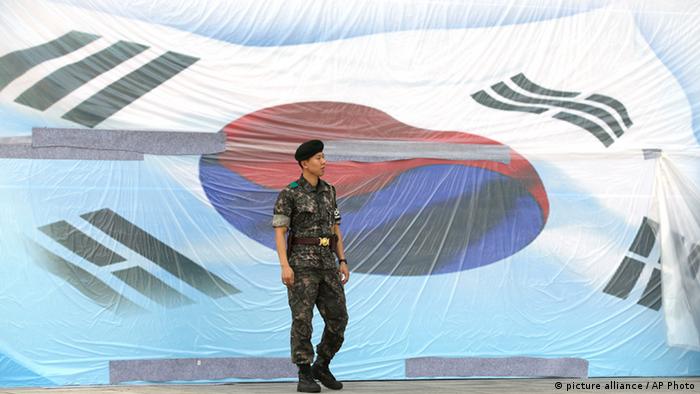 A South Korean soldier stands in front of huge national flag covered with plastic for protection on the eve of Memorial Day ceremony at the National Cemetery in Seoul, South Korea, Wednesday, June 5, 2013. 