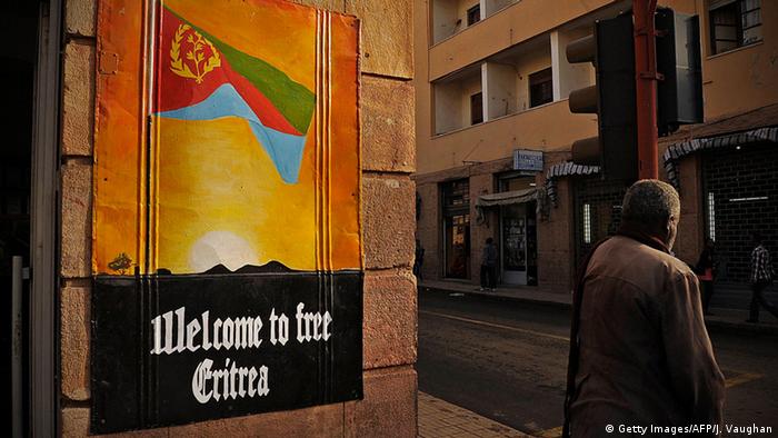 Poster in Asmara reading - welcome to Eritrea. Next to it, a man standing alone
