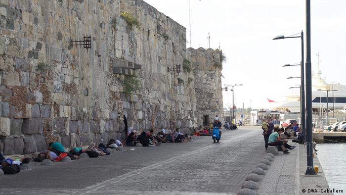Refugees waited in the shade of an old wall hoping to board the Eleftherios Venizelos