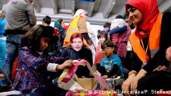Children in an emergency refugee shelter in Germany unpack Christmas gifts