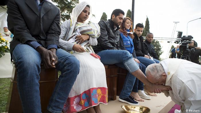 پاپ بر پای یک پناهجو بوسه می‌زند