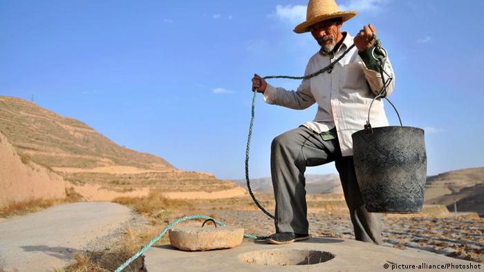 China Bauer holt Wasser an einem Brunnen
