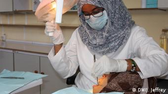 Veiled dentist zainab treating a a woman patient wearing a headscarf