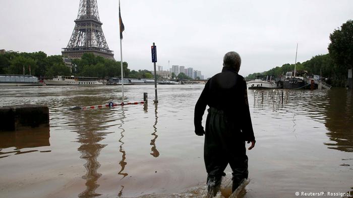 Homem com água até o joelho caminha em rua alagada de Paris