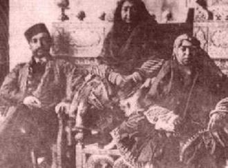 مهد علیا بر روی تخت طاووس (در وسط)، پسرش ناصرالدین شاه و دخترش عزت‌الدوله