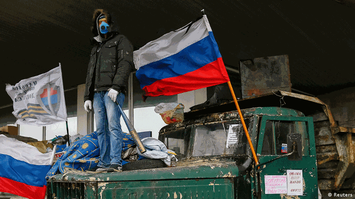 Человек в маске рядом с российским флагом