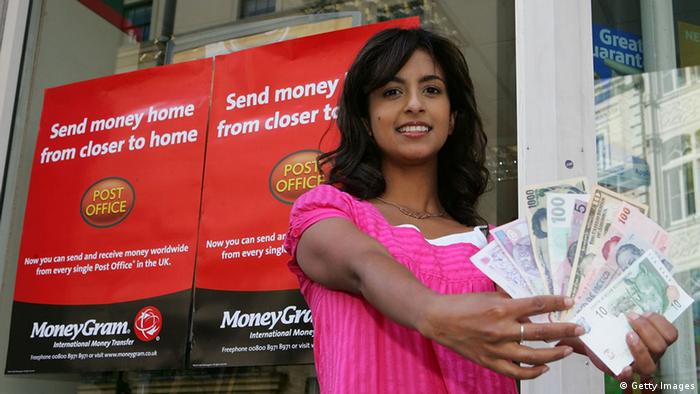 A woman holding a bunch of banknotesd in front of a Moneygram sign (Getty Images)