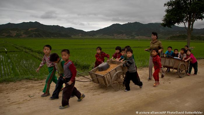 Children repair a road in the rural countryside of North Korea
