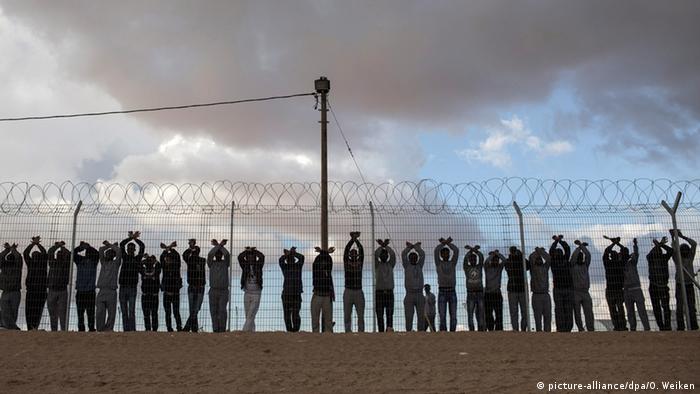 African asylum seekers and inmates of the Holot Detention center stand at the fence of the facility during a protest in Holot, Israel, 17 February 2014 (picture-alliance/dpa/O. Weiken)