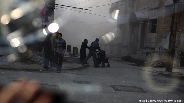 In der syrischen Stadt Duron laufen Menschen über eine Straße. Sie ist ganz nebelig und die Häuser sind zerstört. (Foto: Abd Doumany/AFP/Getty Images)