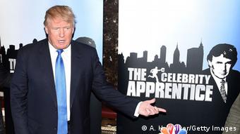 Donald Trump stands next to a 'Celebrity Apprentice' poster