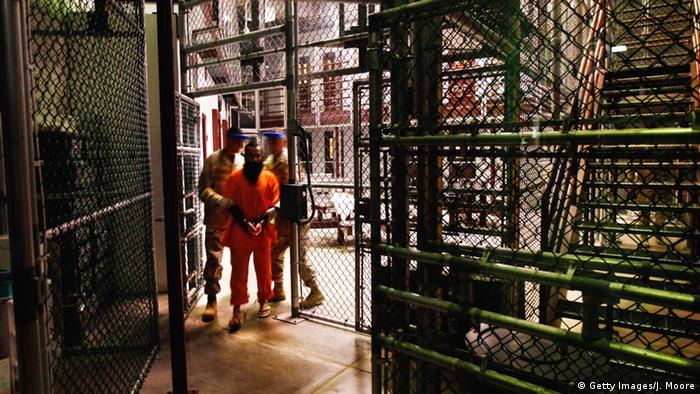 A prisoner being escorted by military personnel at the Guantanamo Bay detention center