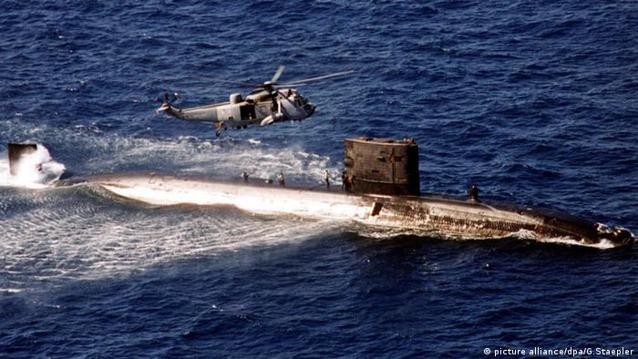 Британская атомная подлодка HMS Turbulent идет по морю, над ней летит вертолет