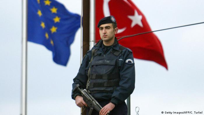 Турецкий полицейский на фоне флагов ЕС и Турции