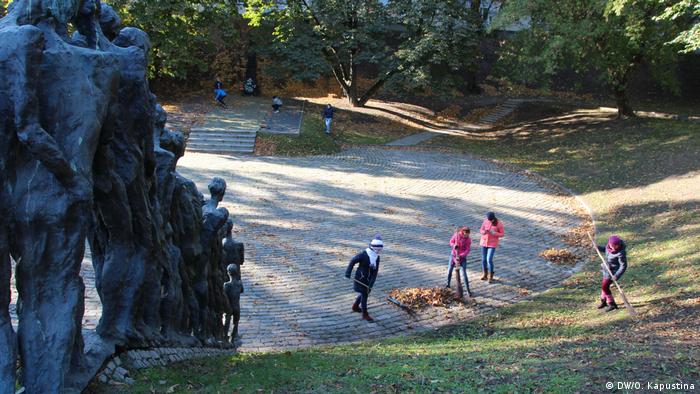 Школьники убирают листву на территории мемориала Яма в Минске