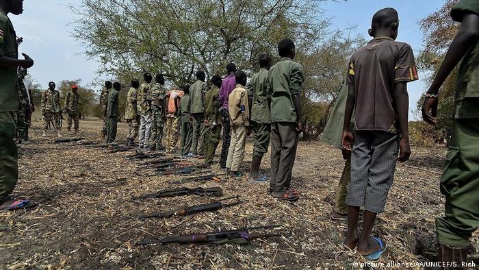 South Sudanese child soldiers standing with their weapons on the floor
