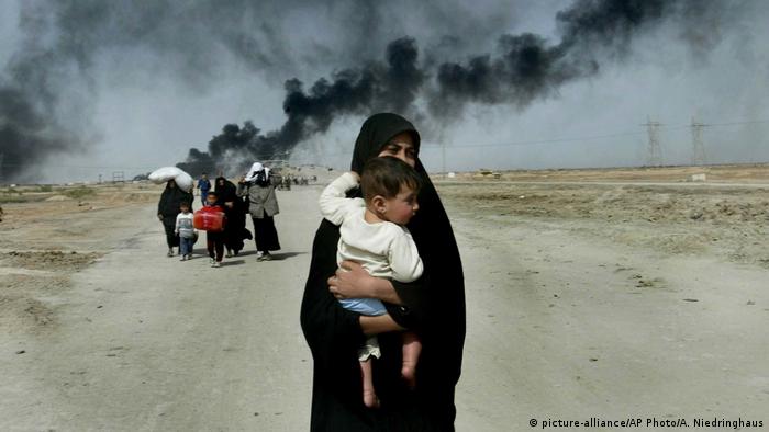 Žene i djeca 30. ožujka 2003. bježe iz Basre, iza njih se vidi crni dim (picture-alliance/AP Photo/A. Niedringhaus)