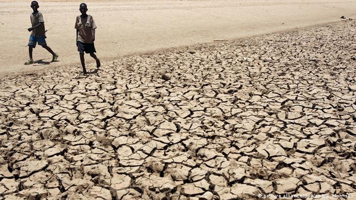 Dois meninos caminham em área seca do Quênia