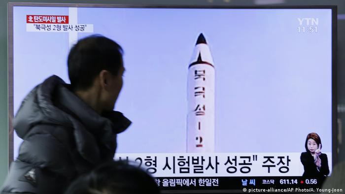 Мужчина перед телеэкраном, на котором показан кадр взлетающей ракеты