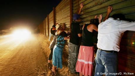 Gente en un muro en la frontera entre México y Estados Unidos.
