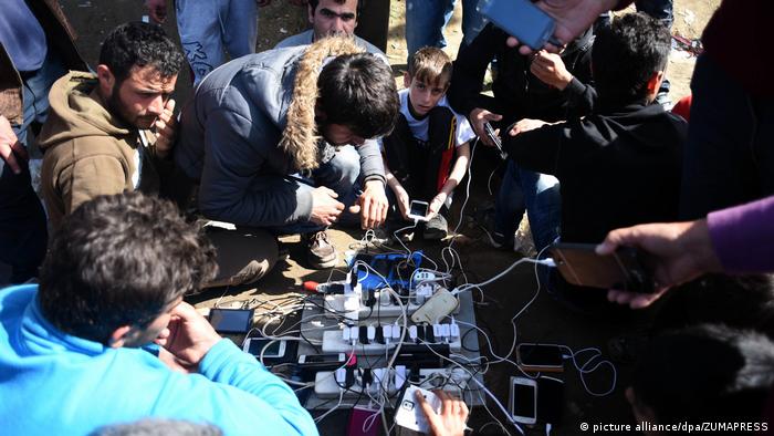 Мигранти зареждат мобилните си телефони на гръцко-македонската граница
