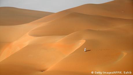 Un hombre de pie en un desierto de arena interminable.