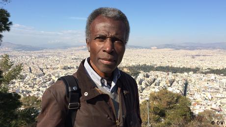 Ο Ακινμπόντε Ακινμπιγί είναι φωτογράφος και εικαστικός καλλιτέχνης με νιγηριανή-βρετανική καταγωγή. Εδώ και χρόνια φωτογραφίζει πόλεις, από το Λάγος ως το Βερολίνο. Στην Αθήνα θέλει να αποτυπώσει μέσα από τον φακό του τα πολλά πρόσωπα της πόλης, αλλά και να δει μέσα από την ελληνική μεγαλούπολη τον δυτικό πολιτισμό.