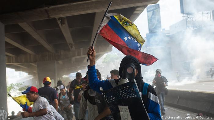 Участники акции протеста в Каракасе убегают от места распыления слезоточивого газа