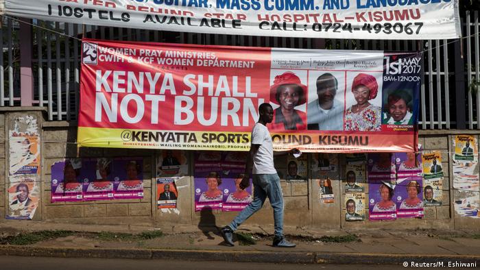 Man walks past a banner saying Kenya shall not burn