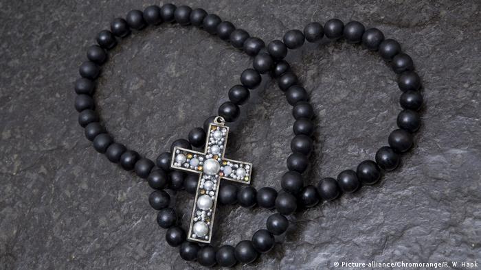 schwarze Perlenkette mit Kruzifix auf Ölschieferplatte (Picture-alliance/Chromorange/R. W. Hapk)