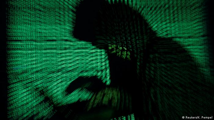 Черная тень человека с ноутбуком в руках на фоне зеленых знаков программного кода