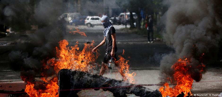 Manifestante caminha atrás de barricada em Caracas