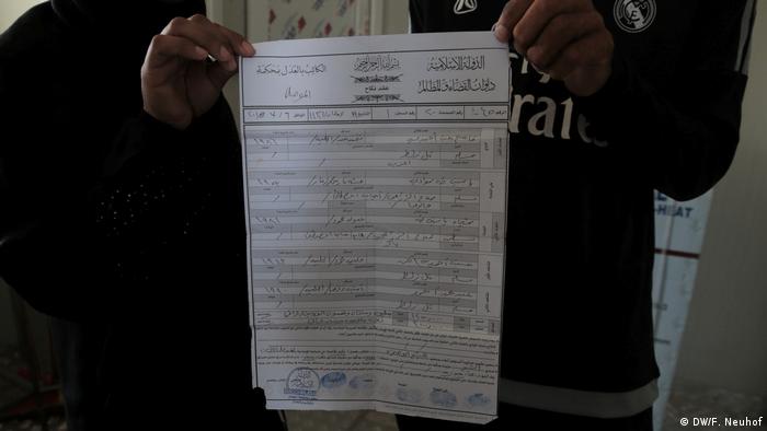 A man holds up a maririage certificate issued by the 'Islamic State' group