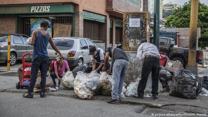 Personas en Caracas, Venezuela, buscan comida en bolsas de basura.