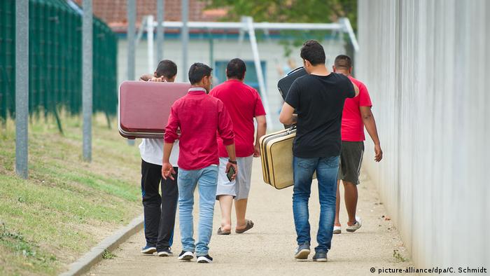 Migrants in Ingelheim, Germany, seen from behind with suitcases (picture-alliance/dpa/C. Schmidt)