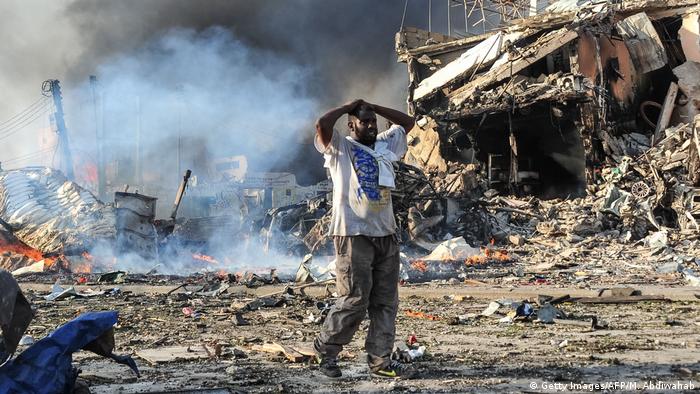 A man holding his hands over his head at the site of a bomb blast