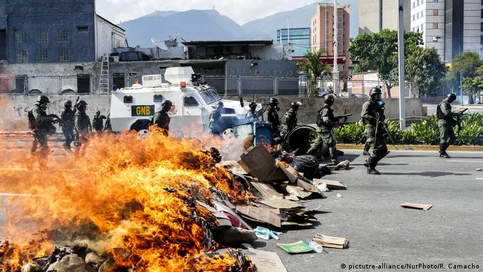 Riot police move past burning barricades in Venezuela (picture-alliance/NurPhoto/R. Camacho)
