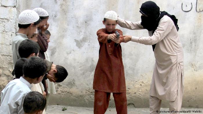 An IS fighter trains children with a handgun (picture-alliance/dpa/G. Habibi)