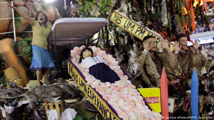 Carro alegórico da Beija-Flor de Nilópolis traz caixão com boneco que representa estudante morto, com críticas à violência, à intolerância e à corrupção