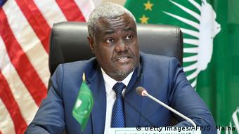 Moussa Faki sits in front of the US and African Union flag
