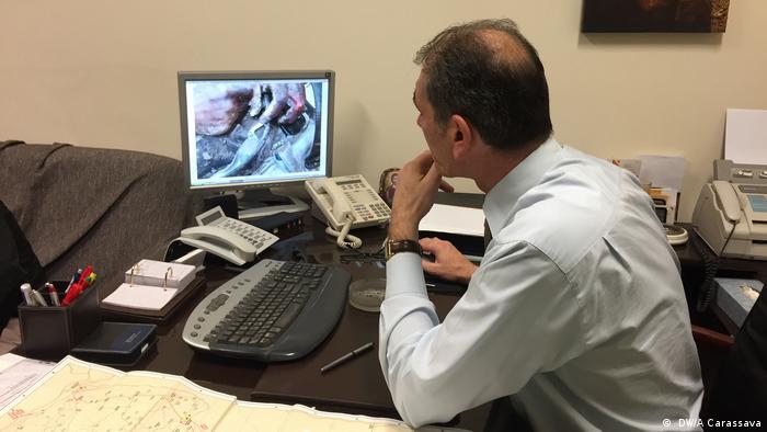 Coroner Pavlos Pavlidis looks at an image of a person found trying to cross the Greek border to get to the EU