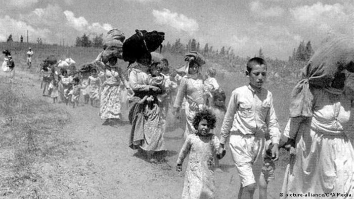 Women and children walk down a dusty road as they leave Palestine (picture-alliance/CPA Media)