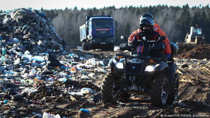Man wearing a gas mask rides a quad bike at the landfill 