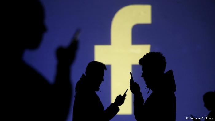Symbolbild Smartphone-Nutzer vor Facebook Logo (Reuters/D. Ruvic)