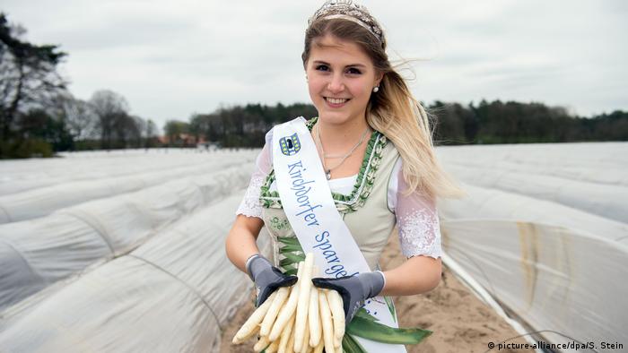 Young woman with a crown holding asparagus in a field (picture-alliance/dpa/S. Stein)
